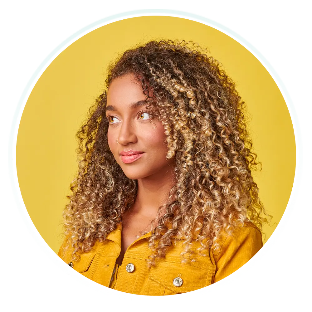 A young woman with curly hair, radiating positivity and confidence.